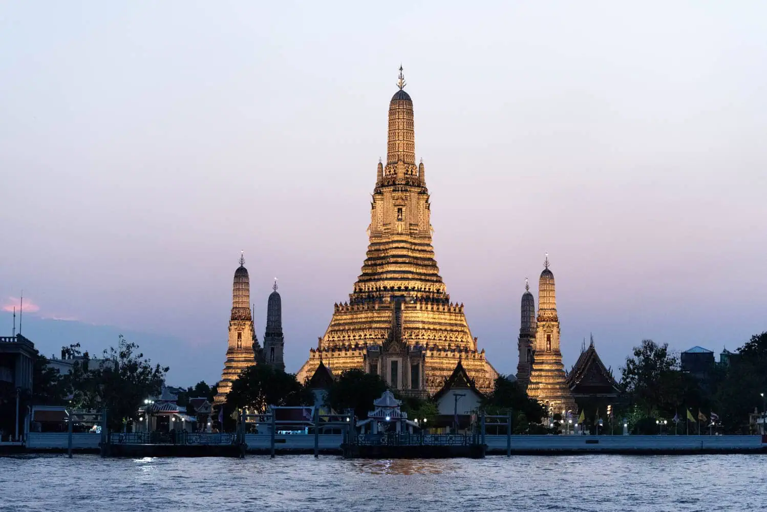 Le temple Wat Arun illuminé au bord du fleuve à Bangkok